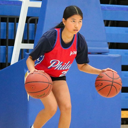 Girl camper dribbling two basketballs